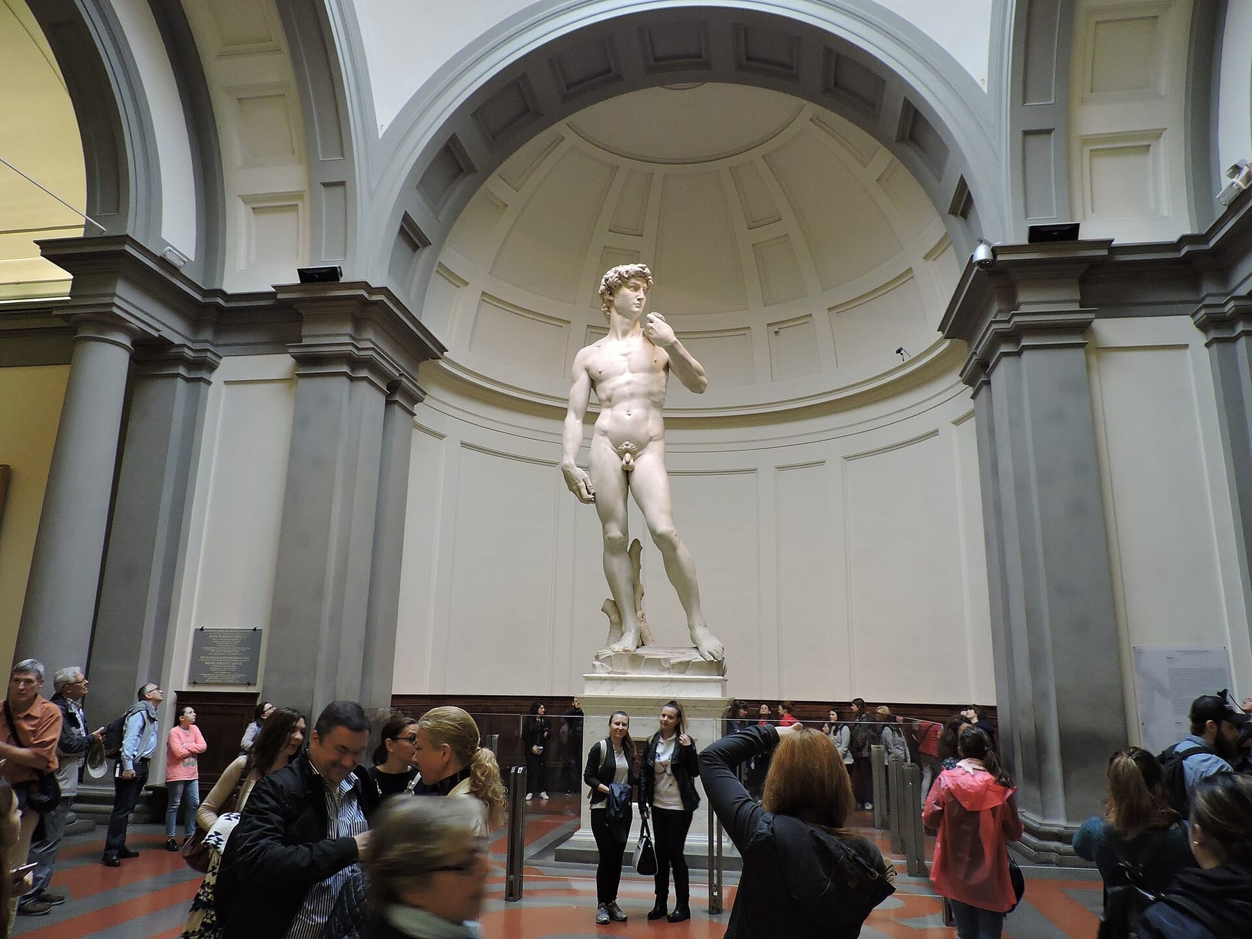 Michelangelo’s David standing in the Tribuna of the Accademia Gallery in Florence, with visitors gathered in front of it