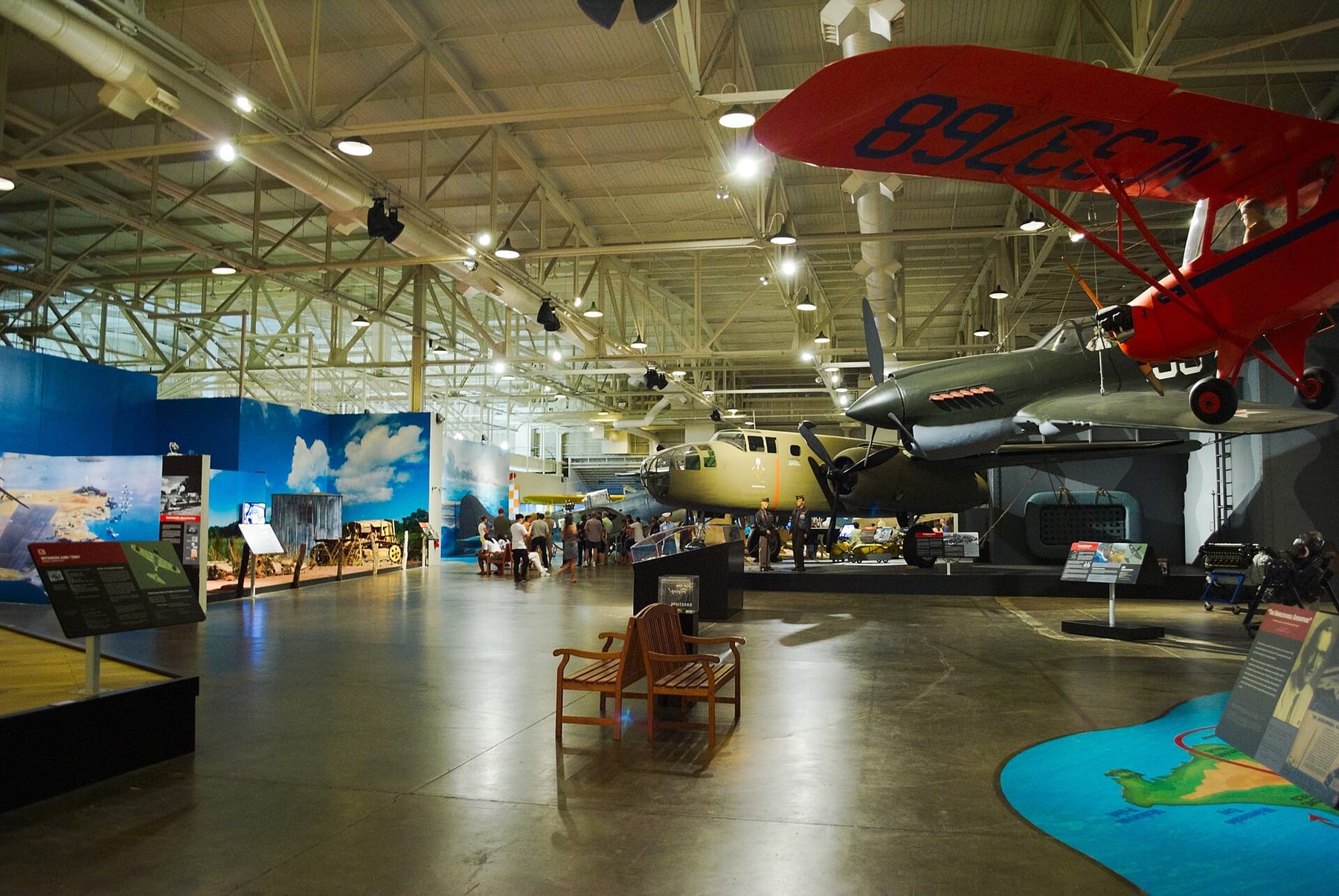 Inside Hangar 37 at the Pearl Harbor Aviation Museum on Ford Island, with a WWII bomber and other aircraft under the steel roof trusses, part of the first ticket on this page