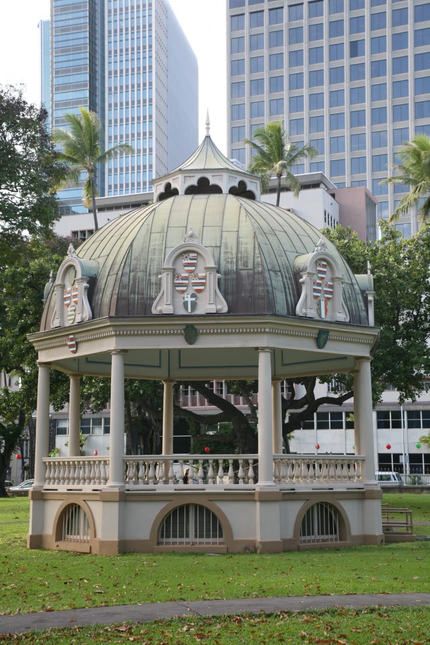 The Coronation Pavilion, a domed Victorian bandstand decorated with royal Hawaiian coats of arms, on the lawn of the Iolani Palace grounds in Honolulu