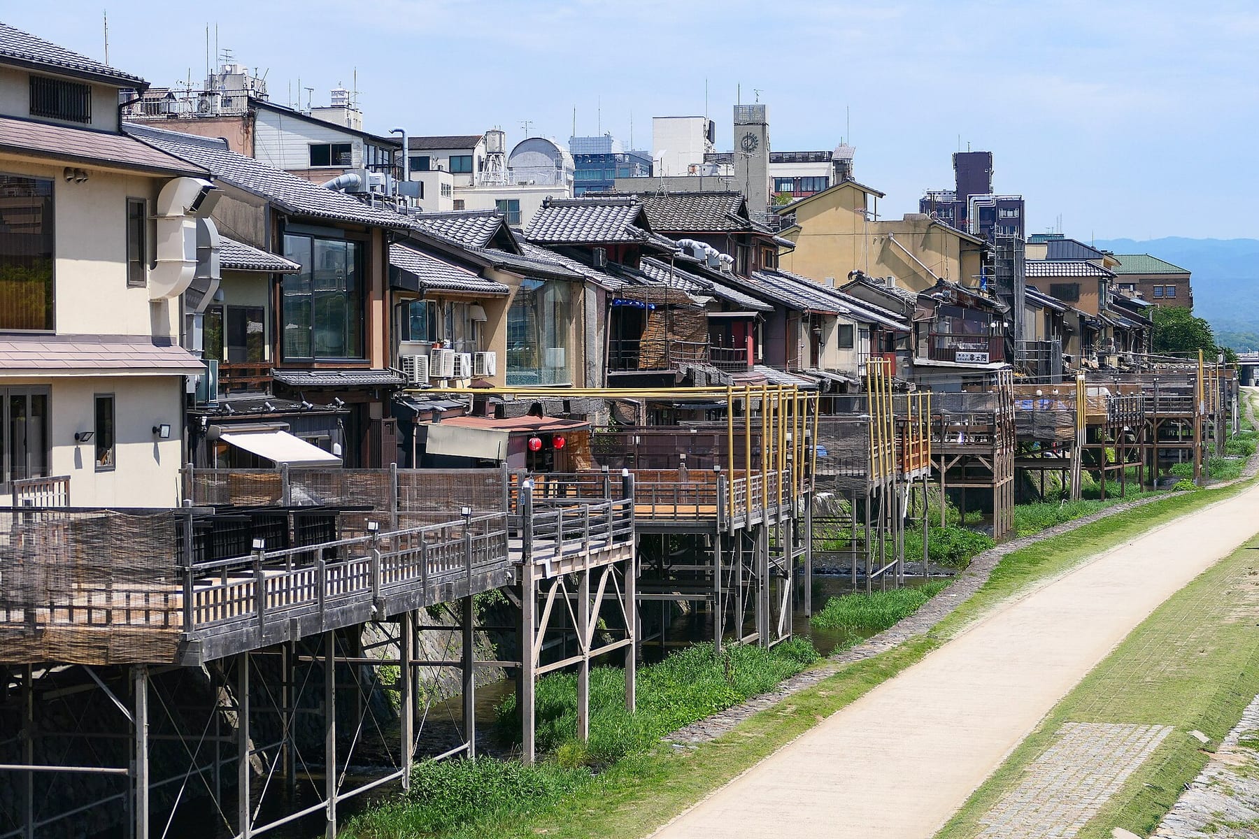 Raised wooden dining platforms on stilts behind Pontocho, above the Kamo River path