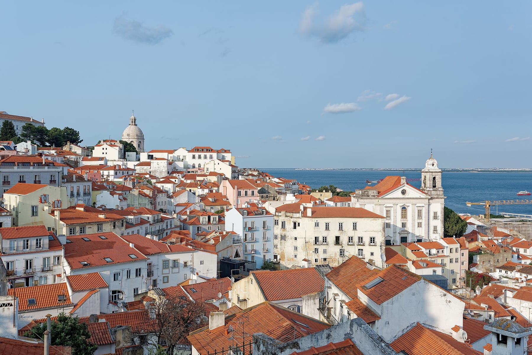 Red-tiled rooftops of Alfama, the Igreja de Santo Estêvão and the Tagus, seen from the Miradouro das Portas do Sol in Lisbon