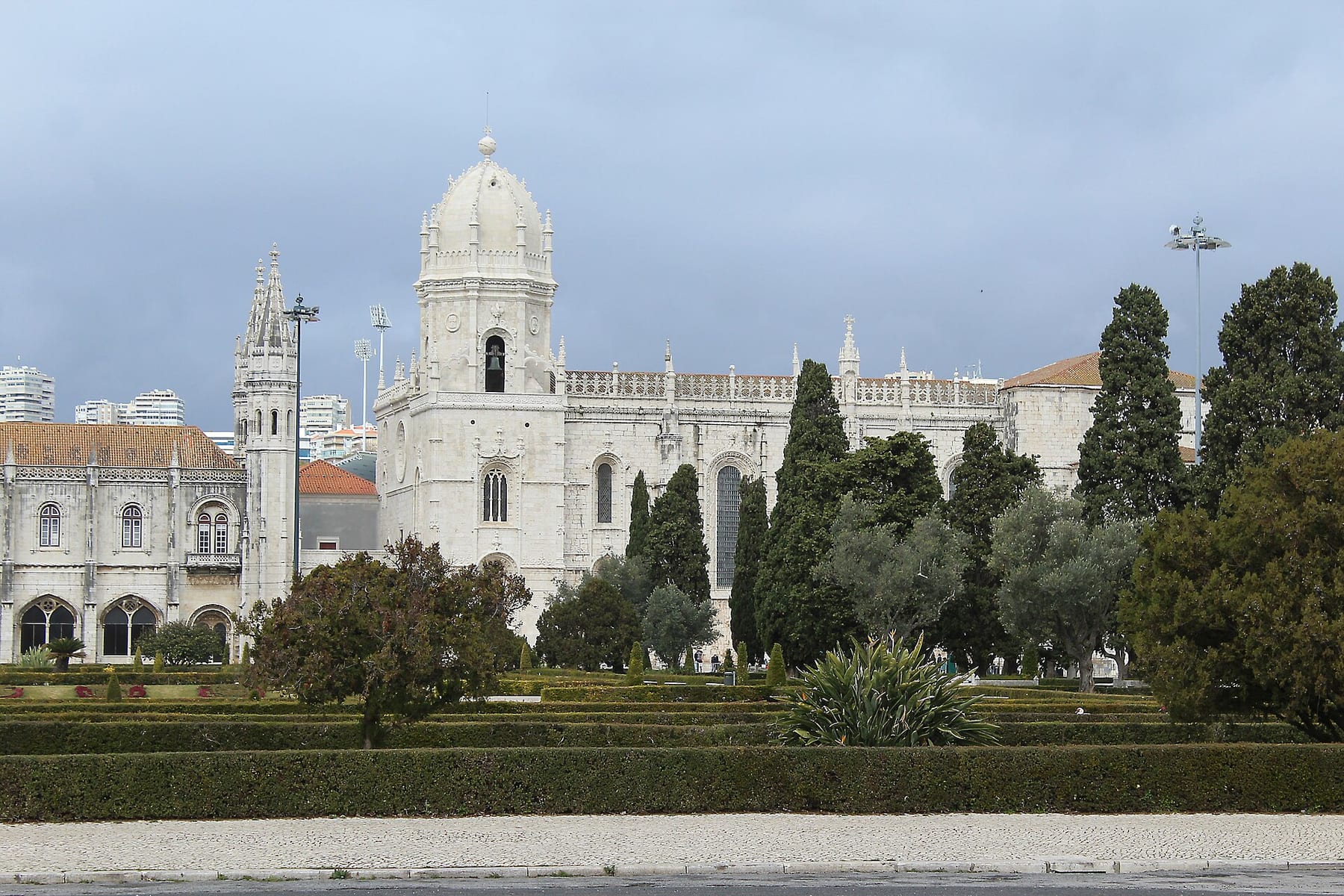 The Jerónimos Monastery, its domed bell tower and carved stonework rising above the gardens of Praça do Império in Belém, Lisbon