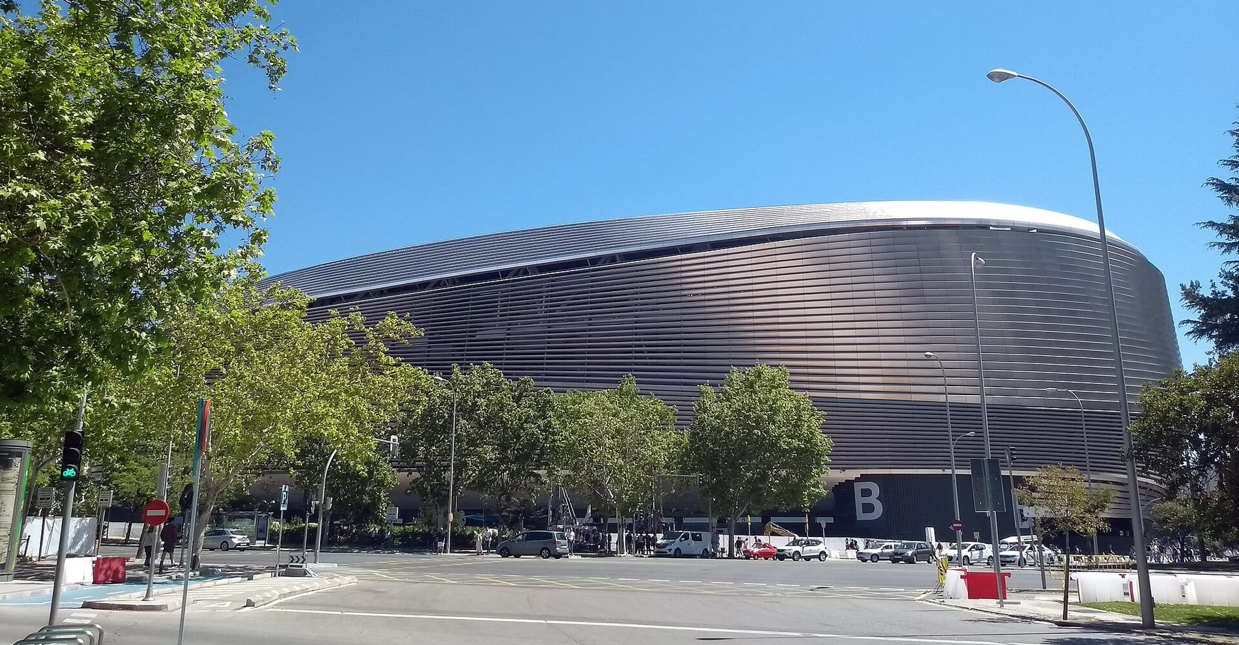 The louvred metal facade and curved roof edge of the renovated Santiago Bernabéu stadium, seen from a street corner on a clear day, one of the three ticketed visits on this page