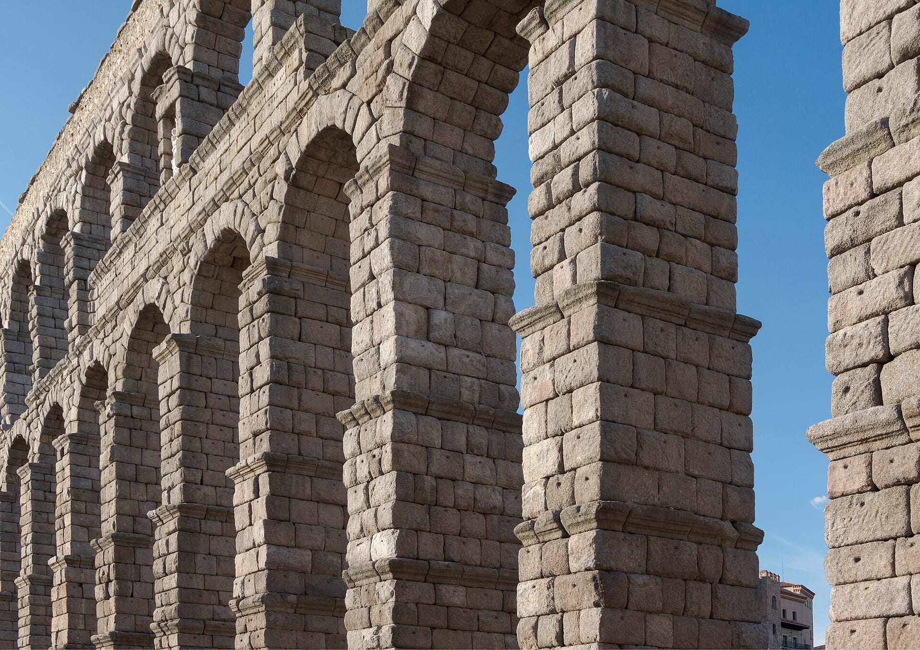 Central arches of the Roman Aqueduct of Segovia, built of stone blocks against a blue sky