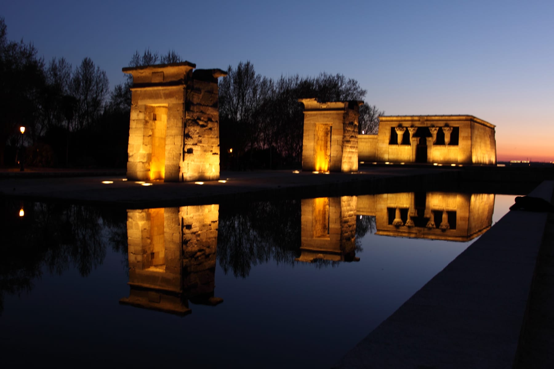 The Egyptian Temple of Debod, its gateways lit at dusk and reflected in the pond in Parque del Oeste, Madrid