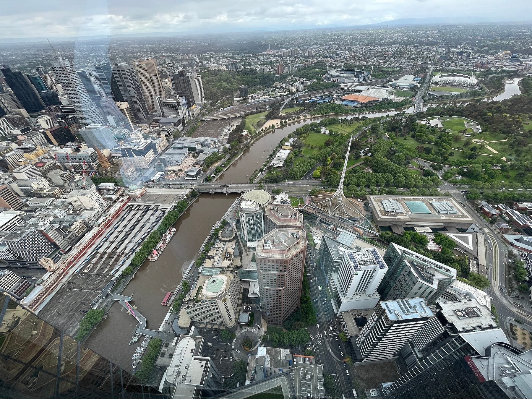 The view from the Melbourne Skydeck observation deck on level 88 of Eureka Tower, looking across the Yarra River, the tracks of Flinders Street Station and the Arts Centre spire, the last stop on this route